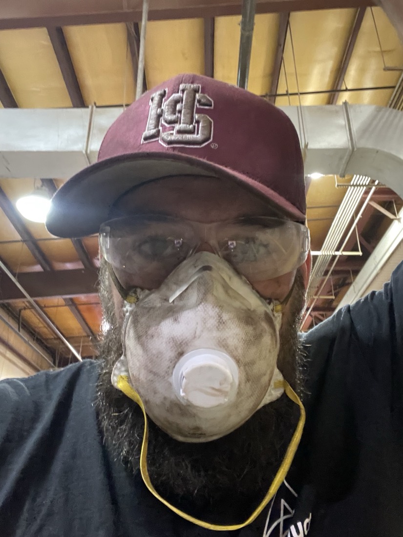 Will, Lua's home services lead, in a dusty respirator and safety glasses on a job site